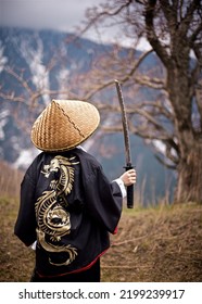 曇りの天候で山道に刀の剣で立っている着物に描かれたドラゴンとサムライに扮した少年の後姿