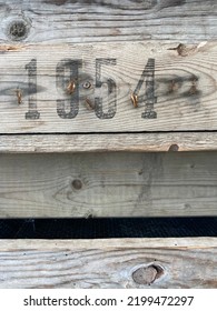 Op een verweerd houten bord staat in zwarte verf het nummer 1954