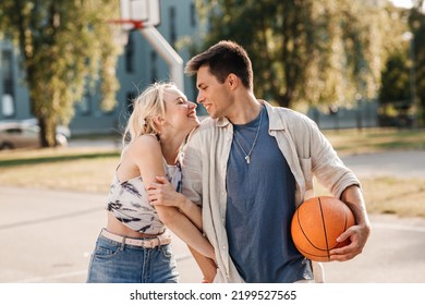 sommerferien, liebes- und menschenkonzept - glückliches junges paar mit ball auf basketballplatz