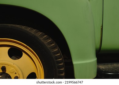 detailweergave van gele velgen van een wiel en de groene carrosserie van een vintage voertuig