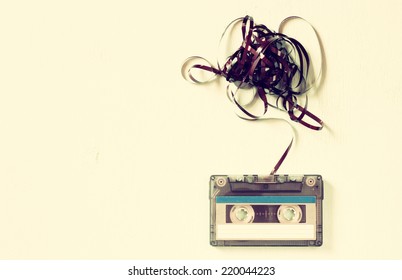 Cassette tape over wooden table with tangled ribbon. top view.  retro filter