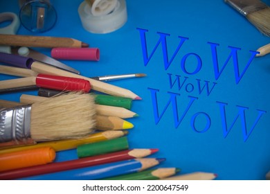 Fotografía cenital de útiles escolares con texto Wow. Pinceles, lápices, herramientas artísticas. Herramientas de trabajo de arte y artesanía.