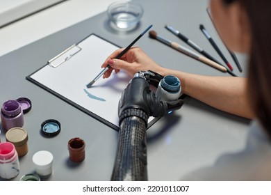 Cận cảnh người phụ nữ trẻ học vẽ bằng sơn trên bàn