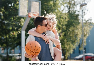 sommerferien, liebes- und menschenkonzept - glückliches junges paar mit ball, das spaß auf basketballspielplatz hat