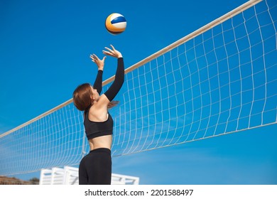 Sporty young women playing beach volleyball match. Professional female volleyball player hit the ball over the net. Summer sports concept.
