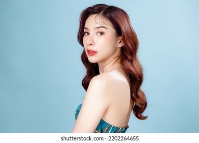 美しい顔と完璧なきれいな新鮮な肌を持つアジアの女性。青の孤立した背景に自然な化粧と輝く目を持つかわいい女性モデル。フェイシャル トリートメント、美容、美容コンセプト。