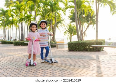 子供乗せスクーター。幸せなアジアの小さな子供の男の子と女の子は、夏の日に屋外の公園の道路で安全なヘルメット遊びキックボードを着用し、外でアクティブな子供のゲーム、子供のスポーツの健康的なライフスタイルのコンセプト