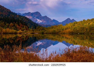 Geweldig herfstavondlandschap. Kleurrijke groene en gele herfstberghellingen weerspiegelen in het meer. Reizen in de Kaukasus, Rusland
