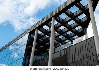Eksterior gedung perkantoran modern dengan fasad kaca dengan latar belakang langit cerah. Dinding kaca transparan gedung perkantoran dengan pantulan awan. Elemen fasad bangunan Eropa modern Komersial