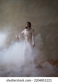 An astronaut on a desert planet alone, an explorer on a distant planet, other worlds and civilizations. A young woman in a retrofuturism-style white spacesuit stands on the sand and looks around