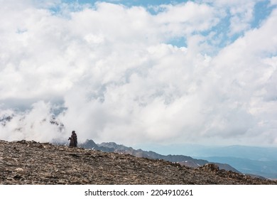 Người đi bộ đường dài và những ngọn núi tuyết cao trong những đám mây thấp dày đặc. Khung cảnh tối giản với con người trên đồi đá dựa vào đỉnh núi tuyệt đẹp trong mây dày. Sự tối giản đơn giản với con người và thiên nhiên núi non hùng vĩ.