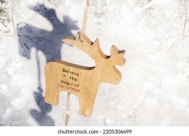Desenfoque de juguete de renos de Navidad sobre fondo de ladrillo, soleado. Juguete de ciervo de invierno modelo pequeño de madera sobre fondo nevado. Ciervo navideño colgando. Concepto de vacaciones de invierno. Maqueta para el diseño. Fuera de foco.