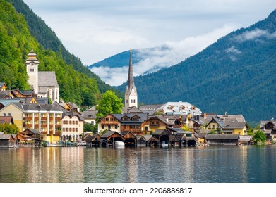 Dorf Hallstatt und Hallstätter See in Österreich. Landschaft mit berühmter alter Kirche in der Nähe des Sees. Wolken und Nebel über den Bergen im Hintergrund. Berühmtes Touristenziel.