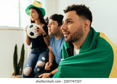 Nervøse og spændte sportsfans, der ser kamp på tv derhjemme. Nervøse venner ser fodboldkamp på sofaen.