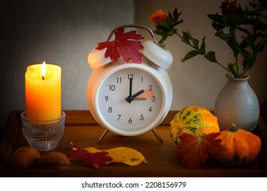 フォールバック、夏時間後の白い目覚まし時計の時間変更、ろうそく、葉、秋の装飾としてのカボチャ、選択したフォーカス