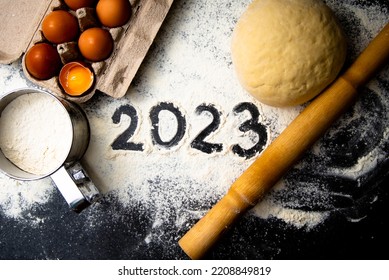 Tepung kue dan nomor 2023 di papan tulis. Pandangan atas. Latar belakang makanan ornamen tahun baru. Buatan rumah.