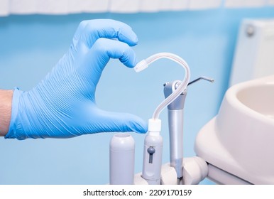 歯科用機器。青い手袋をはめた手と、ハートの形をした唾液排出器。歯科への愛。