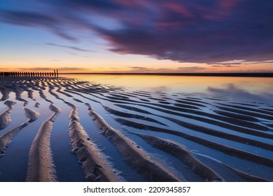 Un paisaje marino durante la puesta de sol. Líneas de arena en la orilla del mar. Cielo brillante durante la puesta de sol. Una playa de arena durante la marea baja. Imagen de viaje. Fotografía para el diseño.