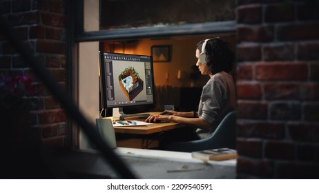 Female Video Game Designer Works on a New 3D Level on Her Personal Computer. Focused Woman Creating Metaverse and Design Video Game. Shot Into the Apartment Window Late at Night.