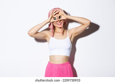 Imagen de una chica graciosa y linda celebrando halloween, vestida de rosa y haciendo muecas, de pie sobre fondo blanco