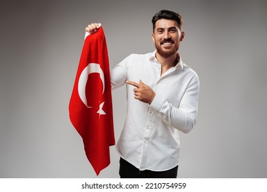 Young businessman holding a flag of Turkey on gray background