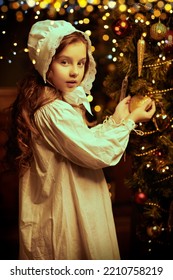 Magic Christmas. A pretty little girl in a nightie and a nightcap admires the beauty of the decorations hanging on the Christmas tree. Vintage style.