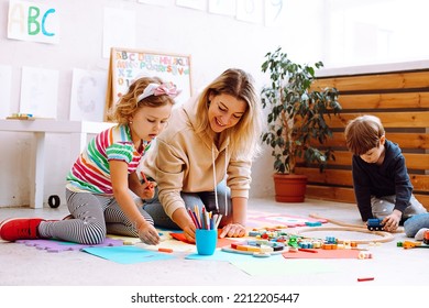 Psikolog wanita yang tersenyum bermain dan menguji anak-anak, membuat kerajinan tangan, mainan buatan tangan dan seni di pusat pengembangan anak untuk anak prasekolah.