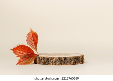 Podio de madera con hojas rojas otoñales, fondo estético minimalista para presentación de productos.