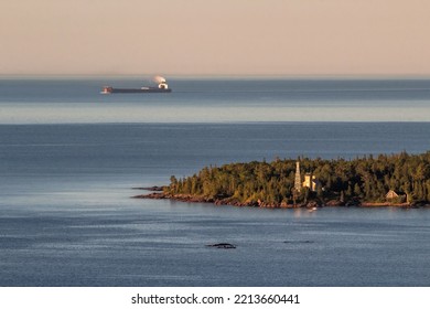 Eine hochwinkelige Teleaufnahme eines Lakers, der während einer goldenen Sommerstunde am Copper Harbor Lighthouse auf der Keweenaw-Halbinsel in Michigan vorbeifährt