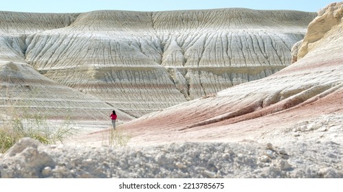 Desert scenery in the Boszhira Valley in the Mangistau region of Kazakhstan in October. Lonely Kazakh girl in pink in the desert.