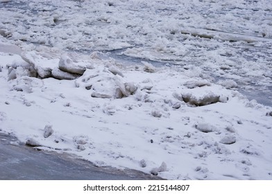 Ais yang dilitupi salji di sungai semasa salji turun. Tekstur musim sejuk. Gula dan ais mengepung.