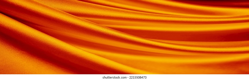 Cortina de cetim de seda laranja. Fundo de luxo brilhante. Design. Tecido drapeado dourado brilhante, dobras. Linhas onduladas. Fluindo. Líquido, ondulação. Dia dos Namorados, Dia das Mães, festivo. Faixa. Largo. Longo. Panorâmico.