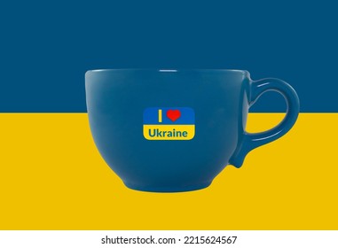 Lege decoratieve gele en blauwe kop op de achtergrond van de nationale vlag van Oekraïne. Op de beker zijn staatssymbolen van Oekraïne aangebracht. Detailopname. Sta achter Oekraïne