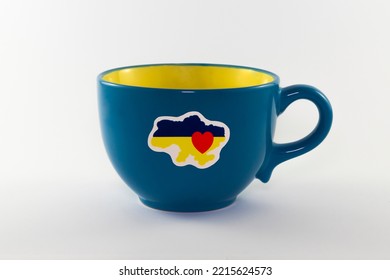 Lege decoratieve gele en blauwe kop die op witte achtergrond wordt geïsoleerd. Op de beker zijn staatssymbolen van Oekraïne aangebracht. Detailopname. Staatsvlag van Oekraïne. Sta achter Oekraïne