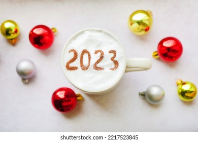 2023 pada tampilan atas busa kopi. Spanduk ucapan Tahun Baru. Cangkir dan ornamen tergeletak datar