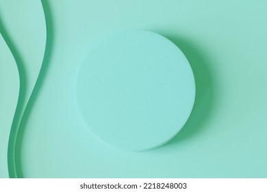 Plataforma de podio con forma geométrica redonda en blanco sobre fondo de color verde pastel con forma geométrica minimalista abstracta cortada en papel. Maqueta de vista superior para exhibición de productos
