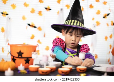 happy Halloween! young girl with  witch costume and making halloween sweets at home
