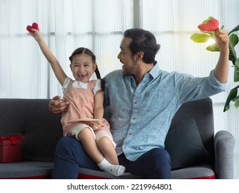 Schöner Vater und süße Tochter, die Hände mit roten Herzen auf die Hände legen und vor Glück lachen. Vatertag oder Geburtstagskonzept.