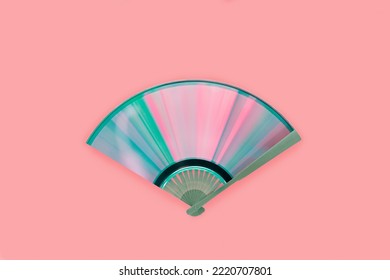 Vista superior del ventilador hecho de disco compacto con reflejos de arco iris sobre fondo rosa aislado. Concepto creativo, retro, abstracto, musical. Difracción de luz en espectro iridiscente rosa-azul-púrpura-verde.