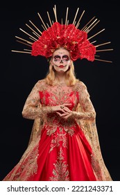 Hermosa Santa Muerte con un festivo vestido rojo dorado y un tocado floral de pie sobre un fondo negro. Retrato de Calavera Catrina. Día de los Muertos. Chica calavera de azúcar. Día de los Muertos. Halloween.
