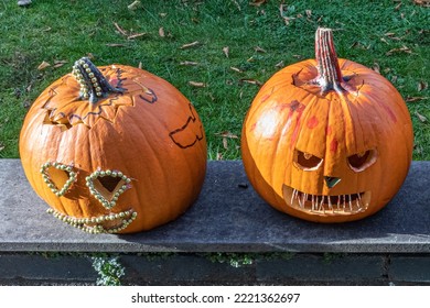 Dos cabezas de calabaza talladas para celebrar Halloween, una con expresión terrorífica y la otra románticamente decorada con pequeñas bolitas doradas, día del terror en la ciudad