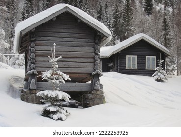 Gammel norsk hytte og lagerhus i træ; 'stabbur' om vinteren. Begge er dækket af sne.