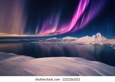 Luces del norte sobre el lago. Aurora borealis con estrellas en el cielo nocturno. Fantástico paisaje mágico épico de invierno de montañas nevadas.