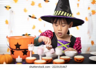 happy Halloween! young girl with  witch costume and making halloween sweets at home