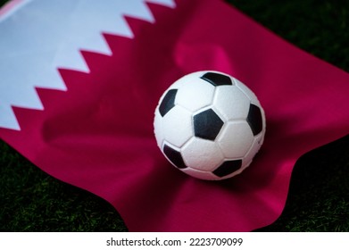 Selección de fútbol de Qatar. Bandera nacional sobre césped verde y balón de fútbol. Fondo de pantalla de fútbol para el campeonato y torneo de 2022. Partido internacional mundial.