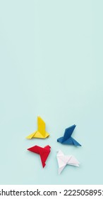banner four paper origami pigeons red, blue, yellow and white on light background, background, vertical, 16:9, copy space