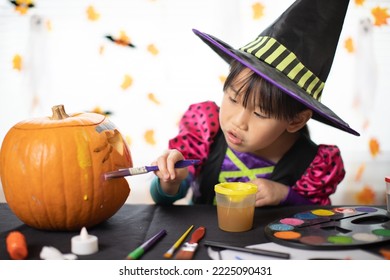happy Halloween! young girl decorating carved pumpkin at home for the party