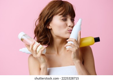 젊은 여성이 얼굴 가까이에 다양한 화장품 병을 들고 행복하게 키스하는 모습을 클로즈업으로 촬영한 사진