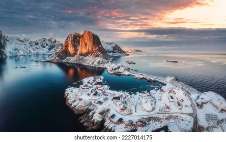 Beautiful landscape of aerial view of snowy mountain and fishing village on coastline in winter at Lofoten Islands, Norway