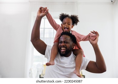 Genéisst glécklech Léift schwaarz Famill afroamerikanesche Papp dréit Duechter klengt afrikanescht Meedchen dat am wäisse Wunnzëmmer doheem laacht. Gléckleche schwaarzen afroamerikanesche Pappendagskonzept.